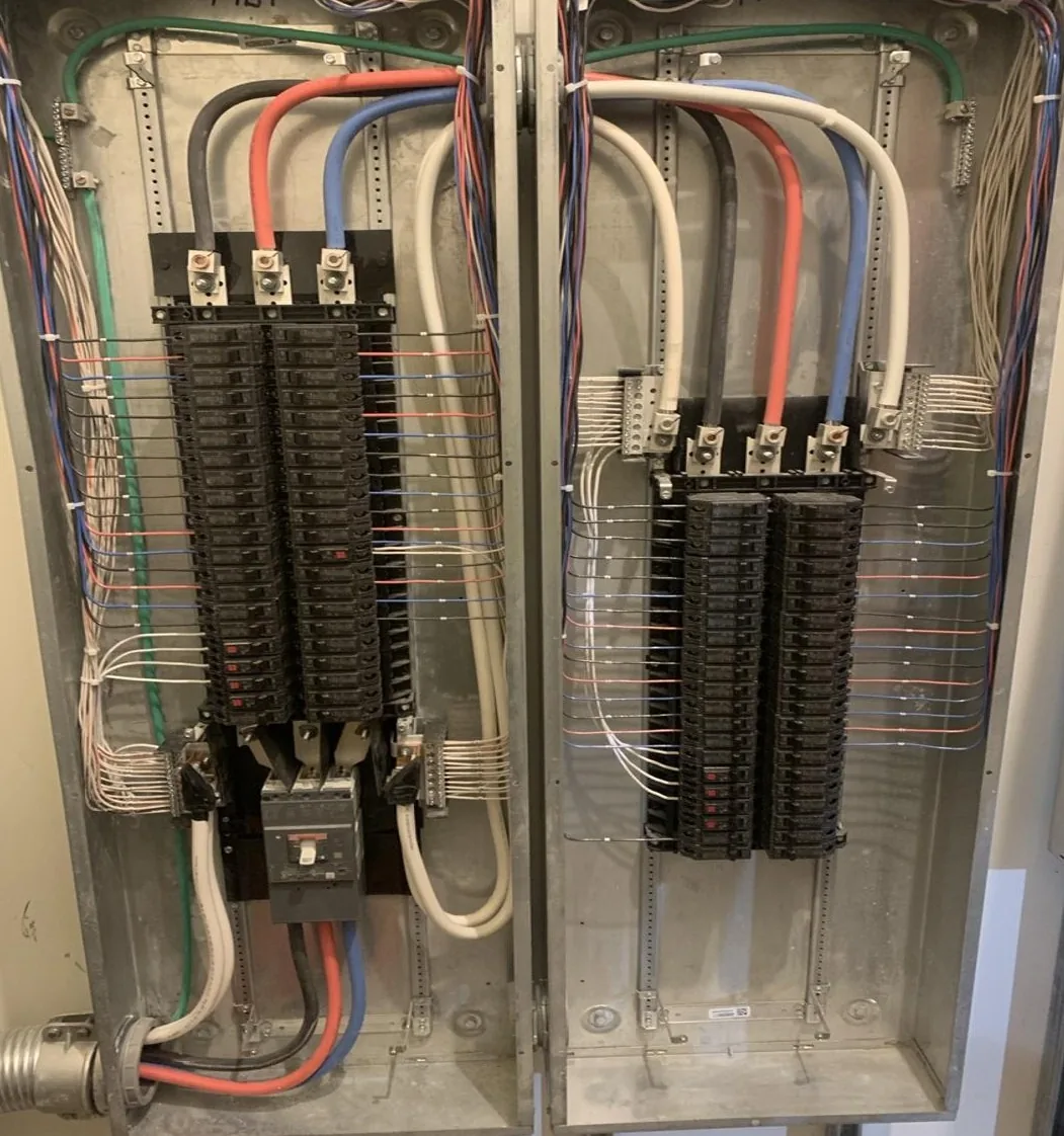 Two open commercial panelboards side by side with neatly dressed branch wiring